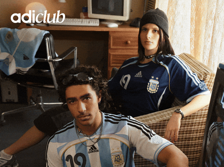 The image shows two individuals, a man and a woman, wearing Adidas sportswear and posing in what appears to be a bedroom or living space setting.