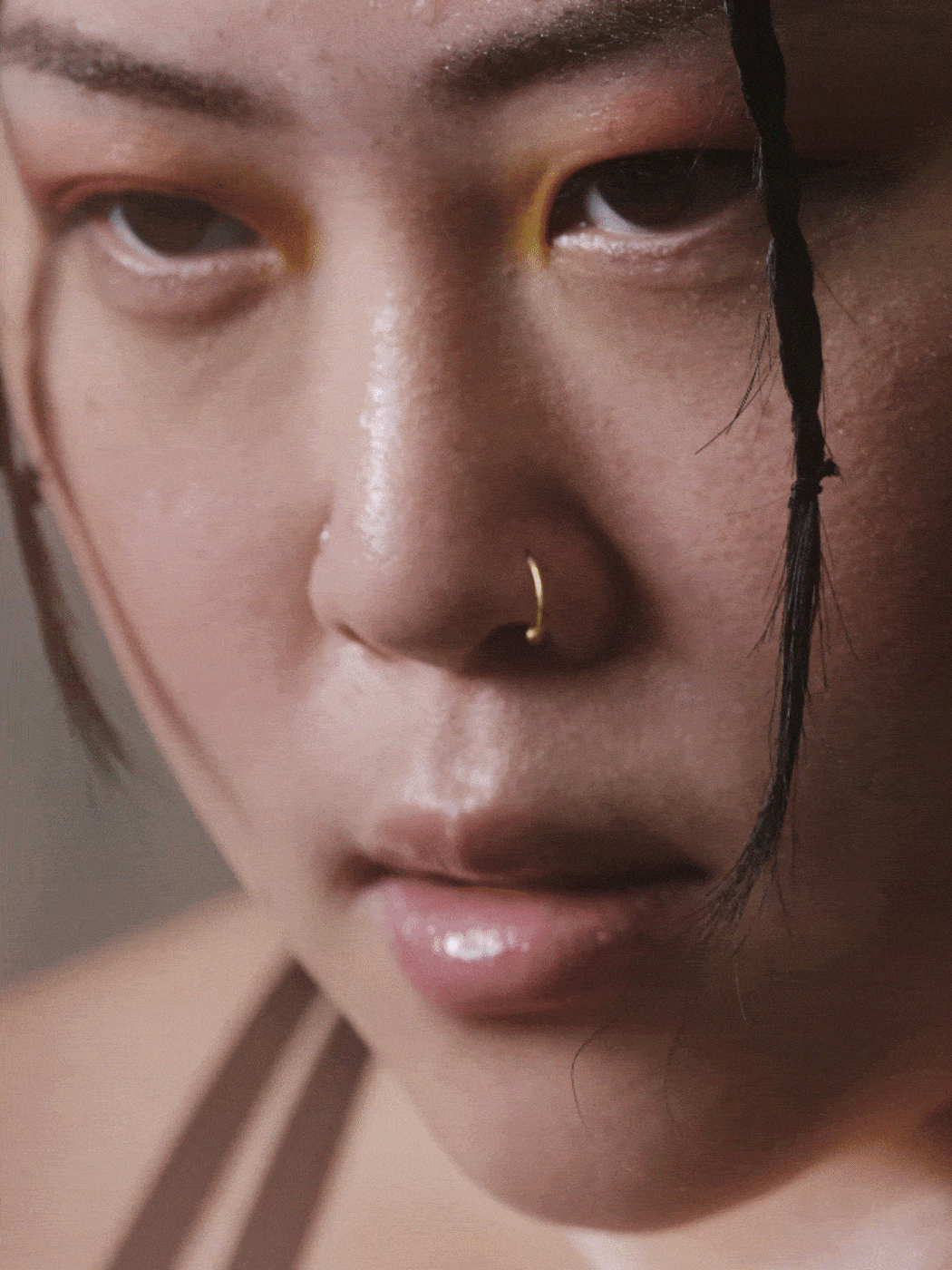 A close-up portrait of a person with a pensive expression, their face partially obscured by strands of dark hair.