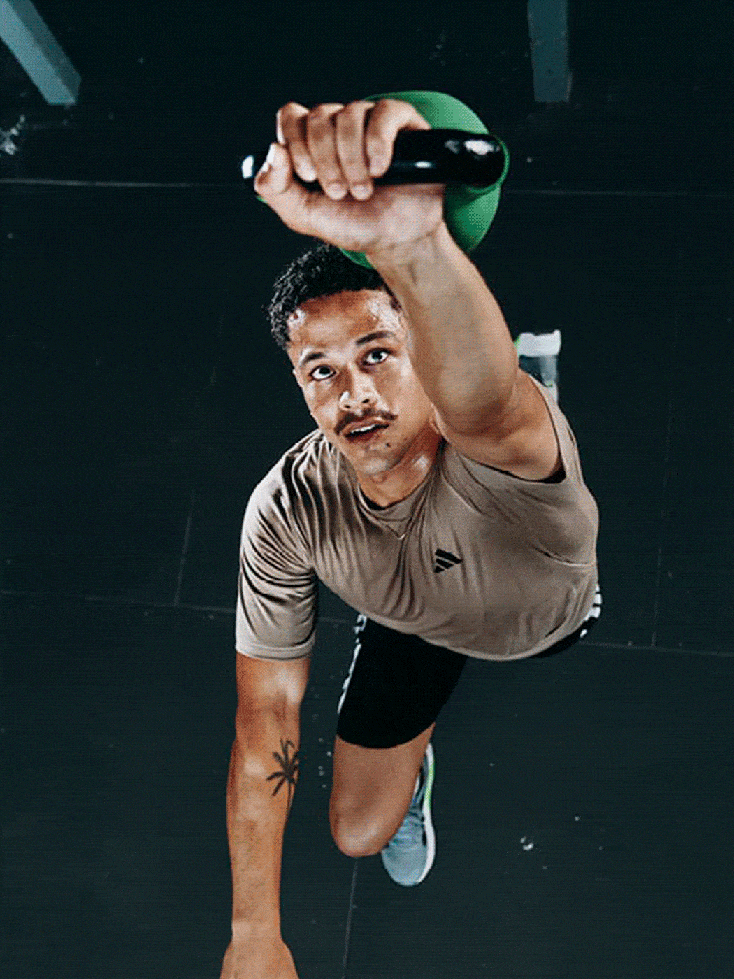A man in a gray shirt is lifting a heavy weight in a dimly lit gym setting.