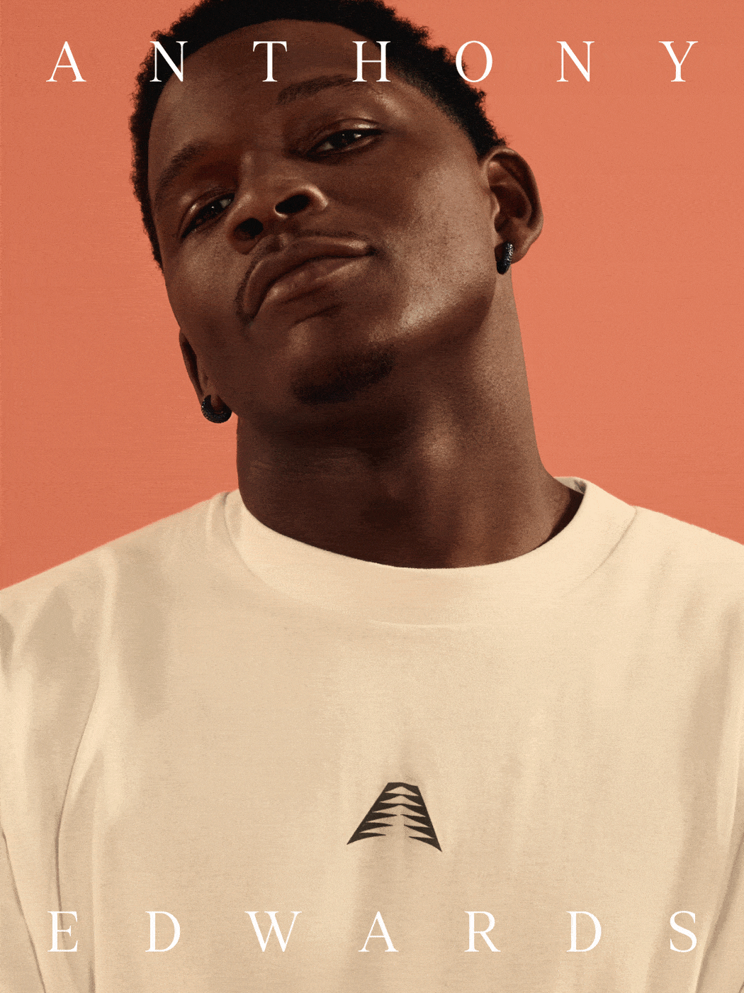 A young Black man with a serious expression, wearing a white t-shirt, against a vibrant orange background.