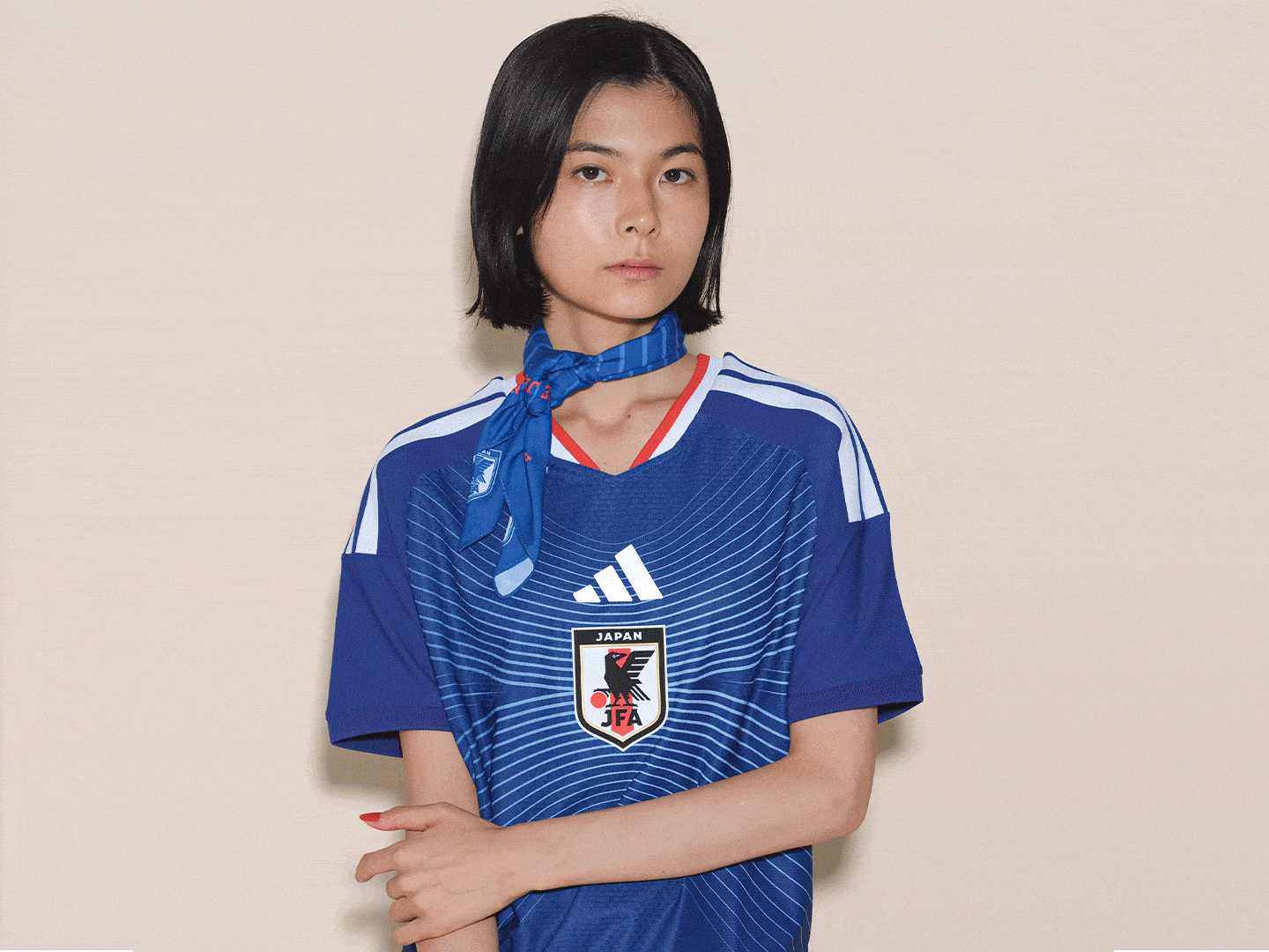 A young woman wearing a blue and white sports jersey stands against a plain beige background.