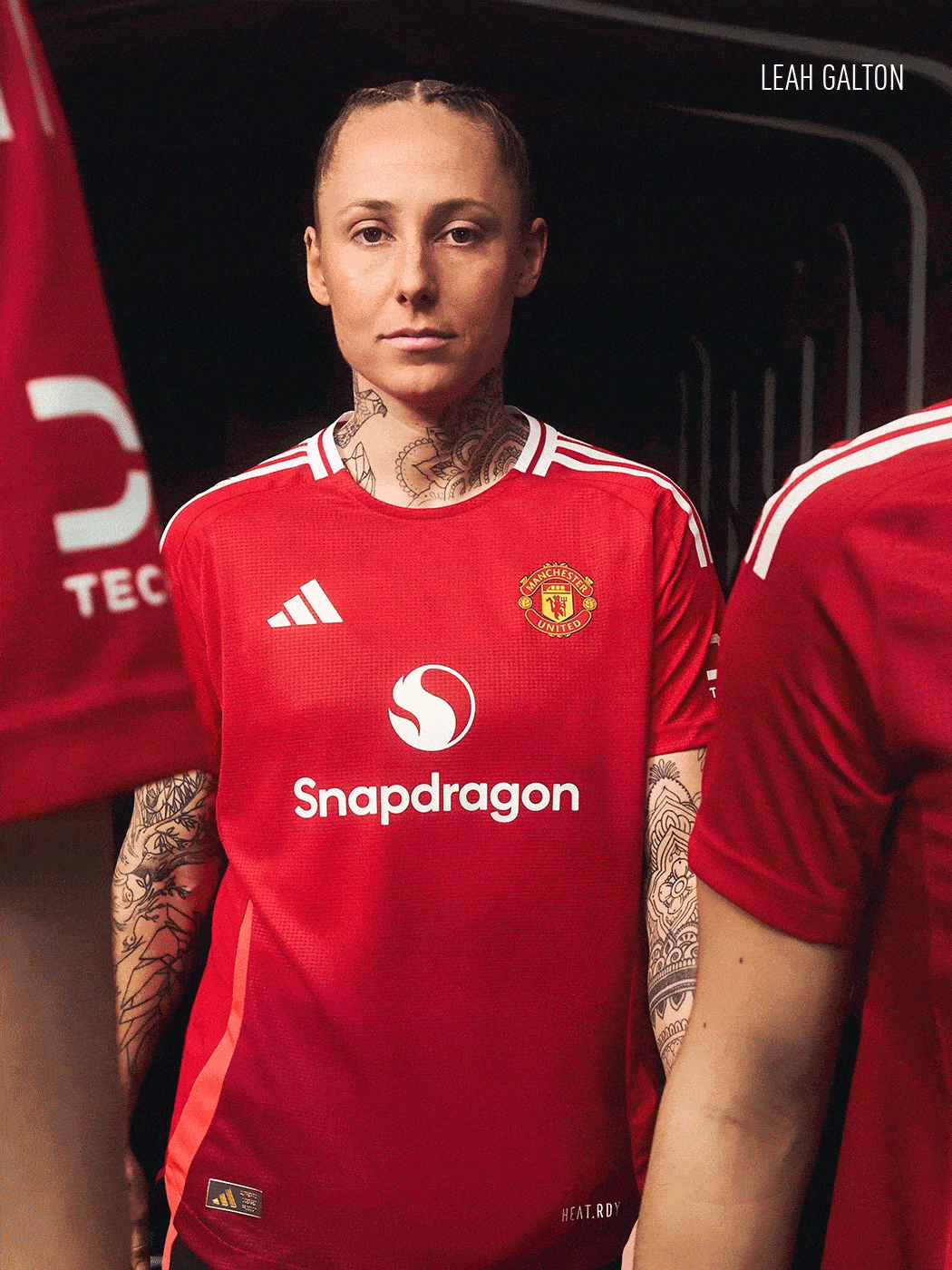 A person wearing a red Manchester United football jersey stands in front of a dark background.