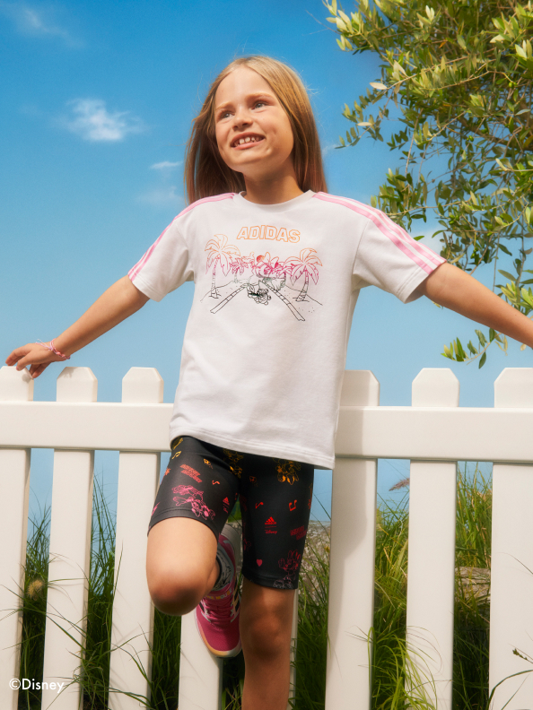 Girl standing by fence smiling wearing adidas | Minnie Mouse collection