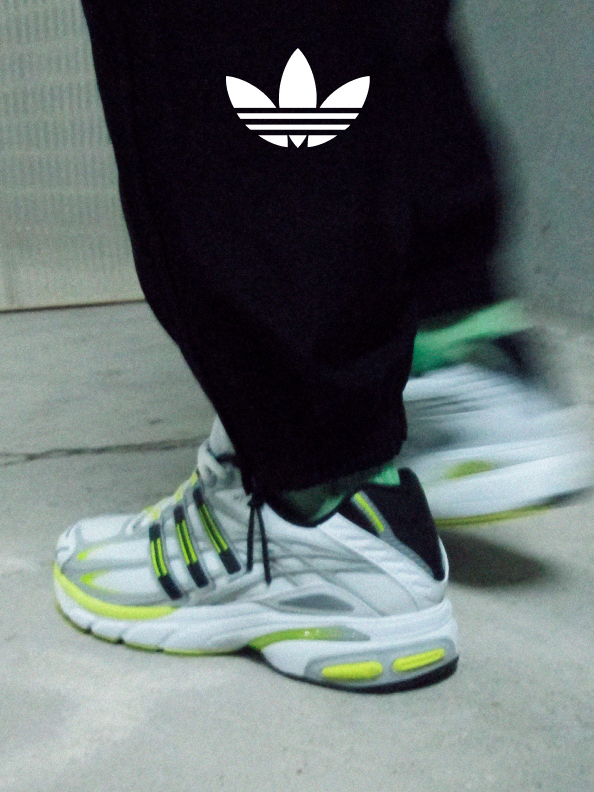 A pair of sneakers from the 2000's Running collection in a dimly lit room with the adidas trefoil logo stamped at the top of the photo.