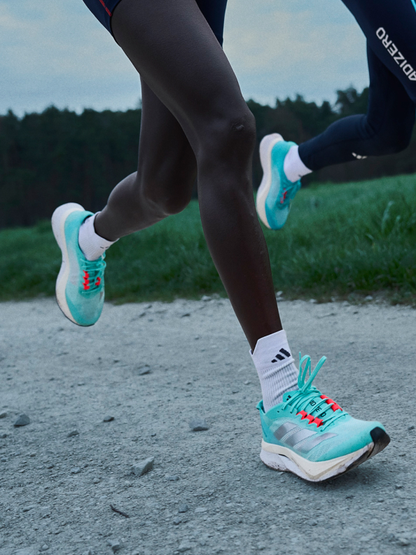 Montage featuring close-ups of Adizero Pro 3 worn by runners in motion, and GIF of Tigist Assefa crossing finish line at Berlin Marathon 2022.