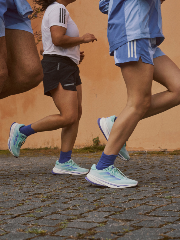 A man and a woman wearing Supernova shoes and adidas running apparel out for a jog in the city. 