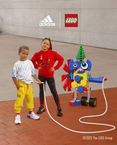 A little boy and girl stand confidently with a LEGO® robot holding a jump rope.