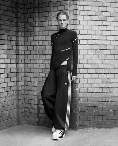 A black and white image captures a model wearing Y-3 in front of a brick wall.