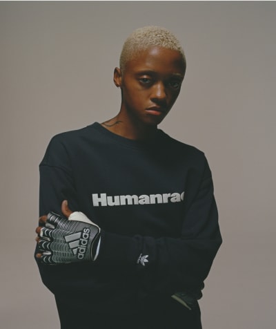 Model wearing navy Humanrace sweater looks to camera against gray background.