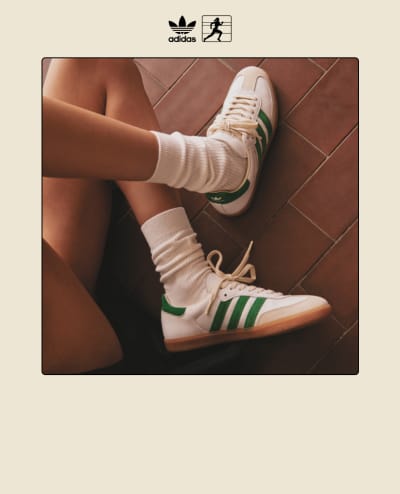 The white adidas X Sporty & Rich Samba OG with green 3-Stripes displayed on foot on a stone floor.