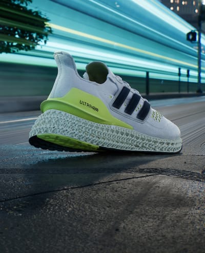 A yellow and white men's running shoe moves forward in an urban environment.