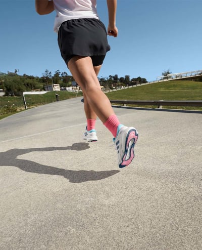 A lower body photo of a women running, wearing adidas Supernova running trainers.