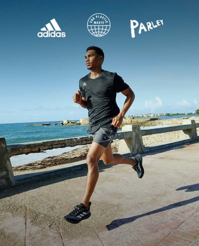 Male running in pair of Parley shoes on seashore.