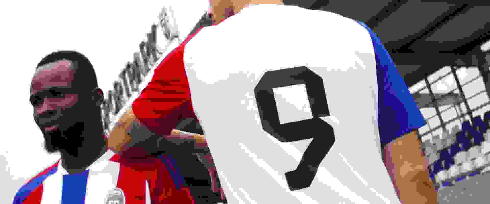 Two people wearing sports uniforms, one in a red jersey and the other in a black jersey, standing outdoors against a cloudy sky background.