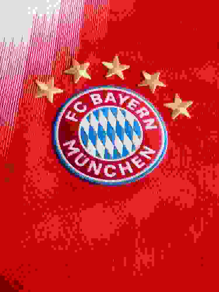 The image shows a man wearing a red and white soccer jersey with the Bayern Munich logo, standing in front of a red background.
