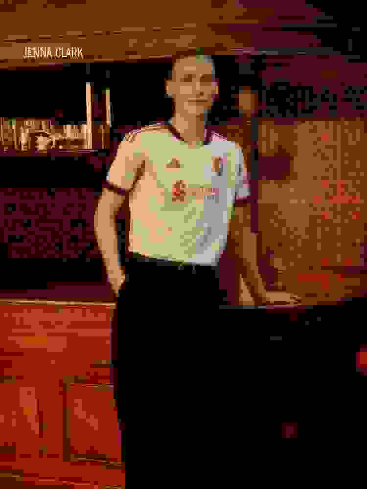 Two men wearing red soccer jerseys with the team's sponsor logos stand in a dark background, their faces visible.