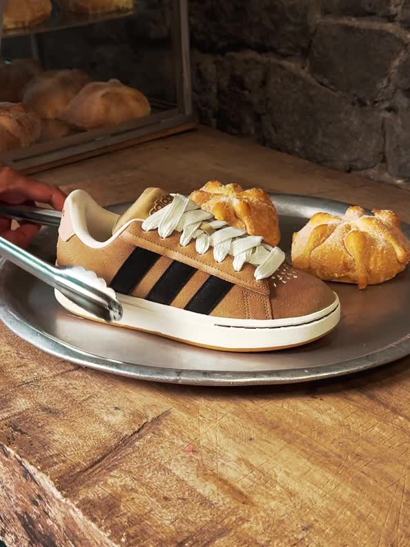 A pair of sneakers sits on a metal tray alongside freshly baked pastries in a rustic, stone-walled bakery setting.