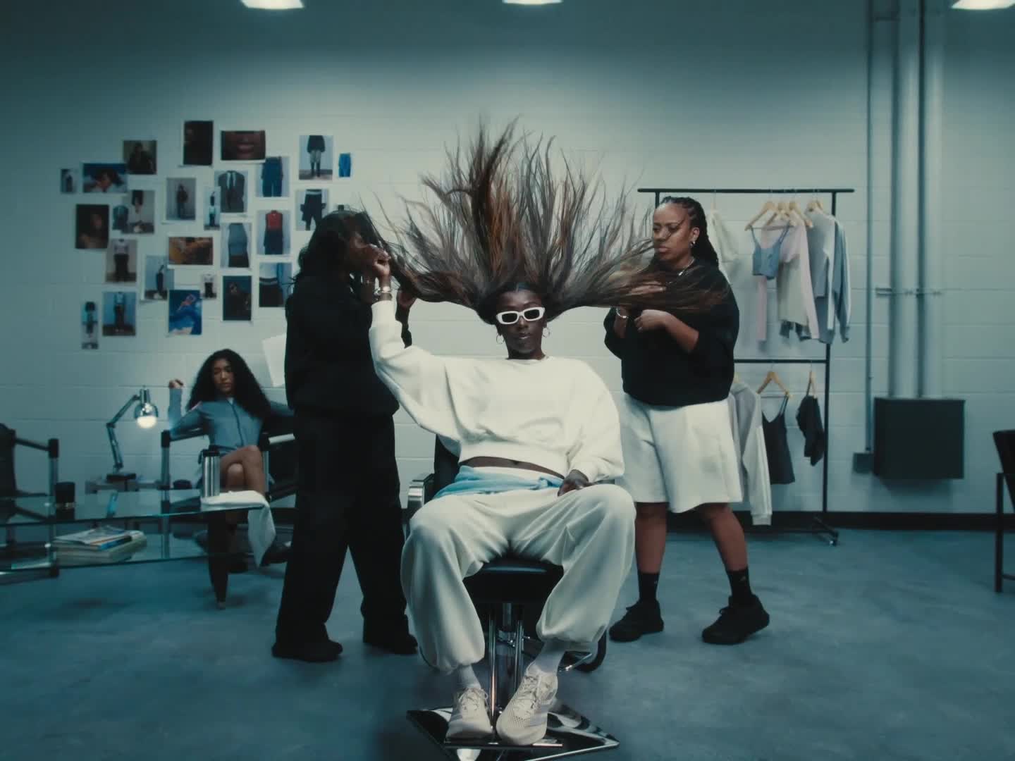 A close-up view of a pair of white and blue athletic shoes with a textured, mesh-like upper, set against a blurred, teal-colored background.