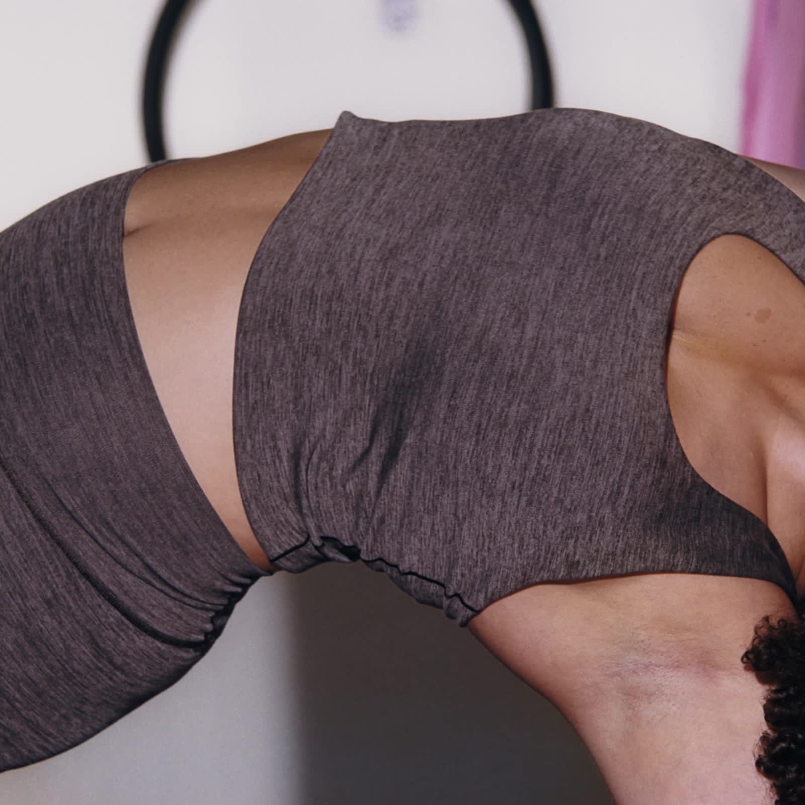 La imagen muestra el torso y la zona del abdomen de una persona, vestida con una camiseta deportiva gris oscuro, sobre un fondo borroso.