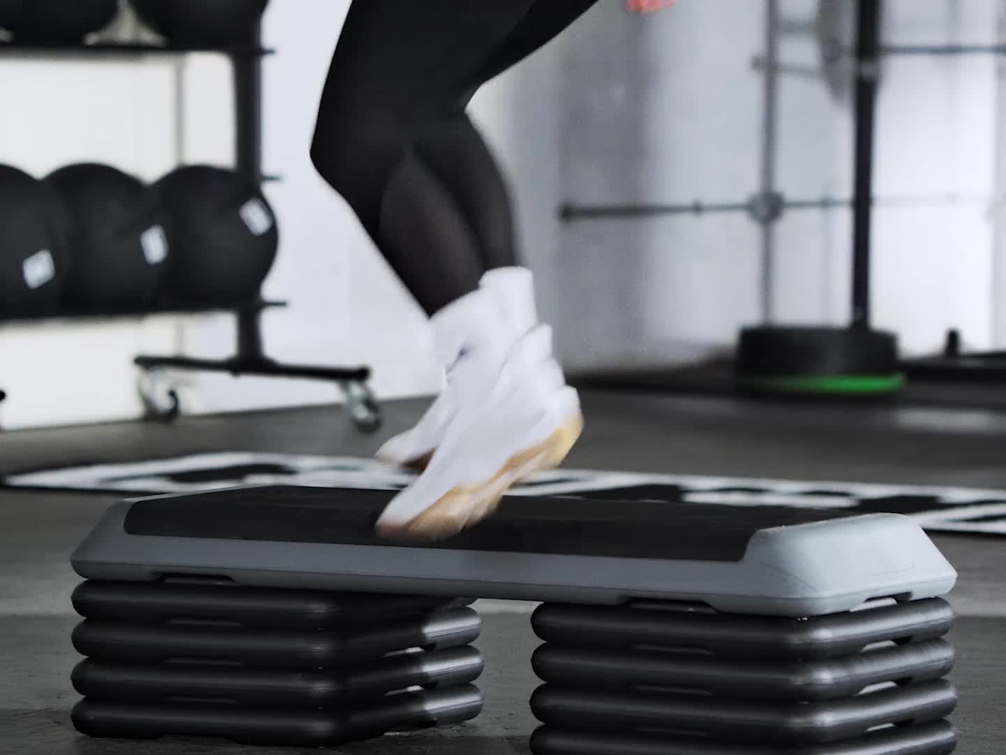 A close-up view of a person's feet wearing white athletic shoes with the Adidas logo on a dark surface.