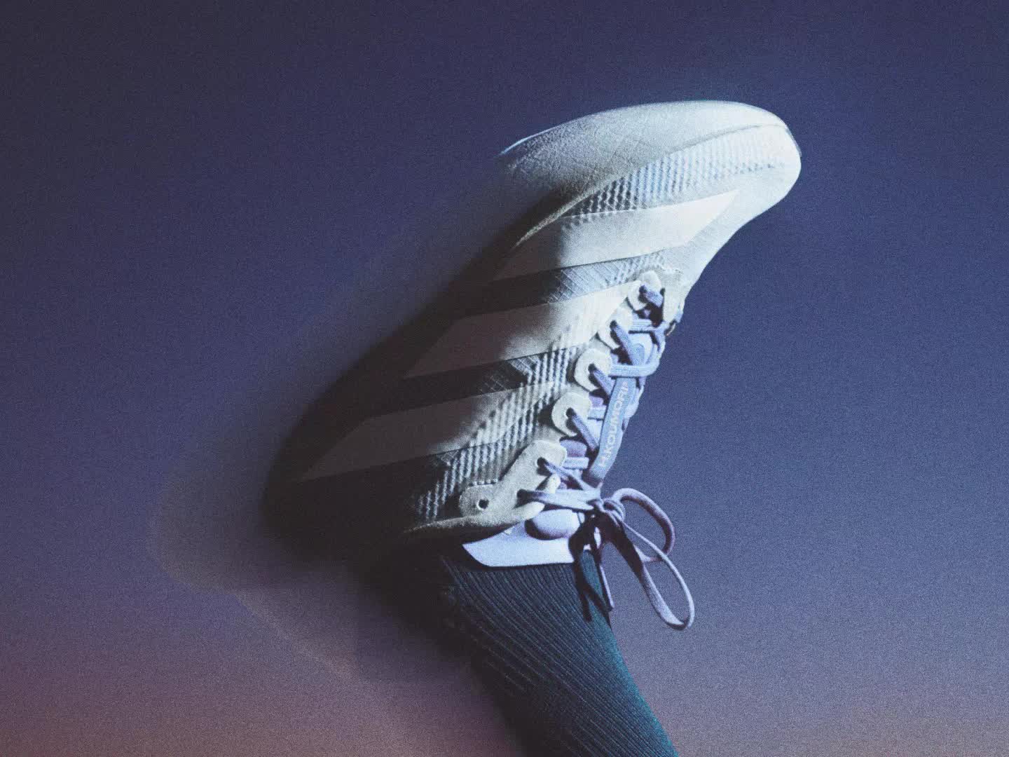 The image shows a close-up view of a person's feet wearing white sneakers on a gravel or rocky surface.