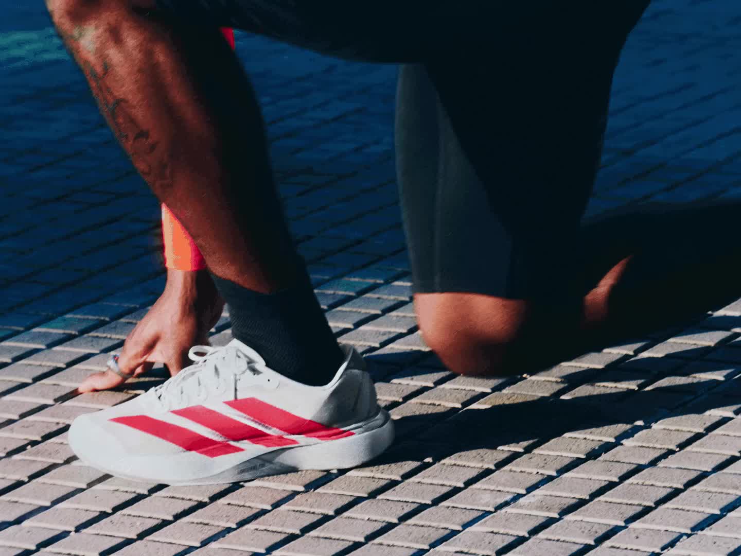 A person in athletic clothing stands in a dimly lit outdoor setting, with a concrete wall or structure visible in the background.