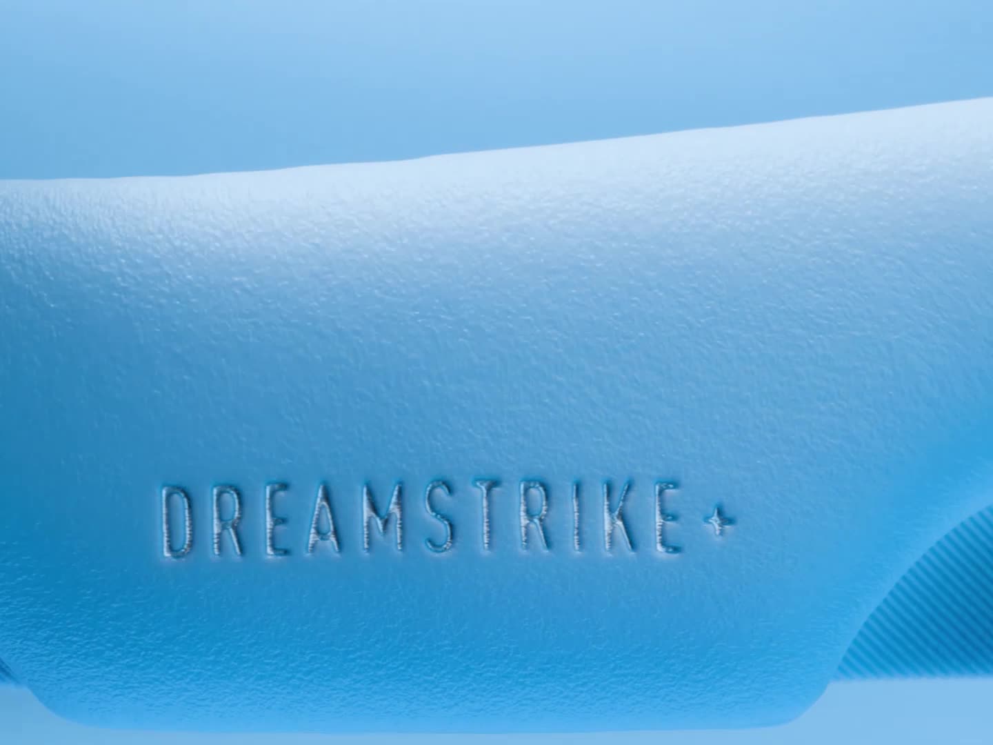 A person's feet wearing blue and white athletic shoes standing on a dirt path in a natural setting.