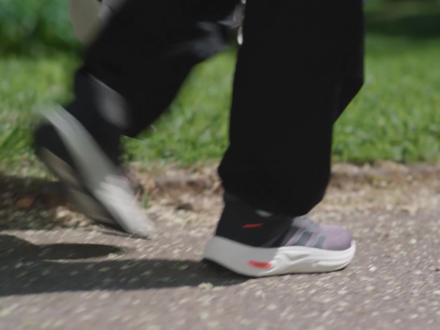 A close-up view of a pair of white and gray athletic shoes resting on a grassy surface, with a blurred background suggesting an outdoor setting.