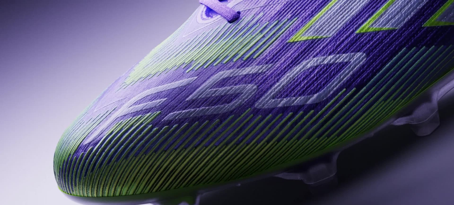 A futuristic-looking, purple-colored device is illuminated against a dark background, casting a bright beam of light.