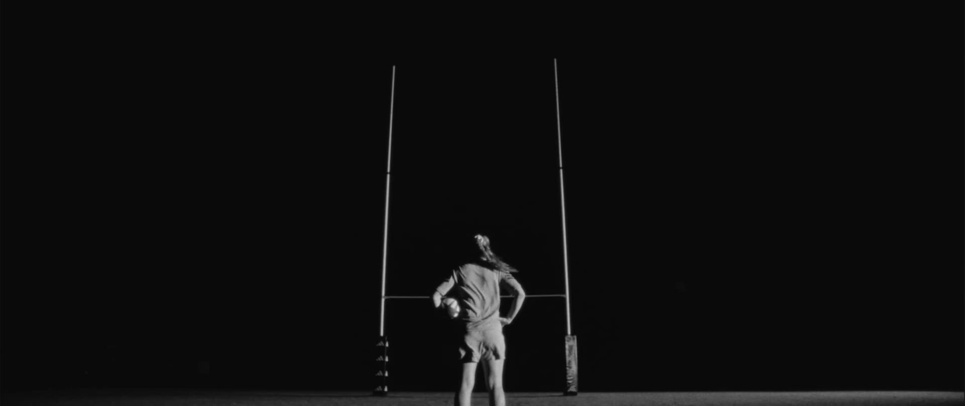 Close-up on a rugby player's legs on the field, wearing the adidas RS15 Avaglide rugby boots in black