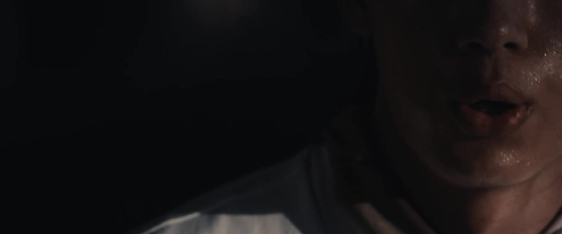 A hand wearing a red and white boxing glove is raised against a cloudy sky background.