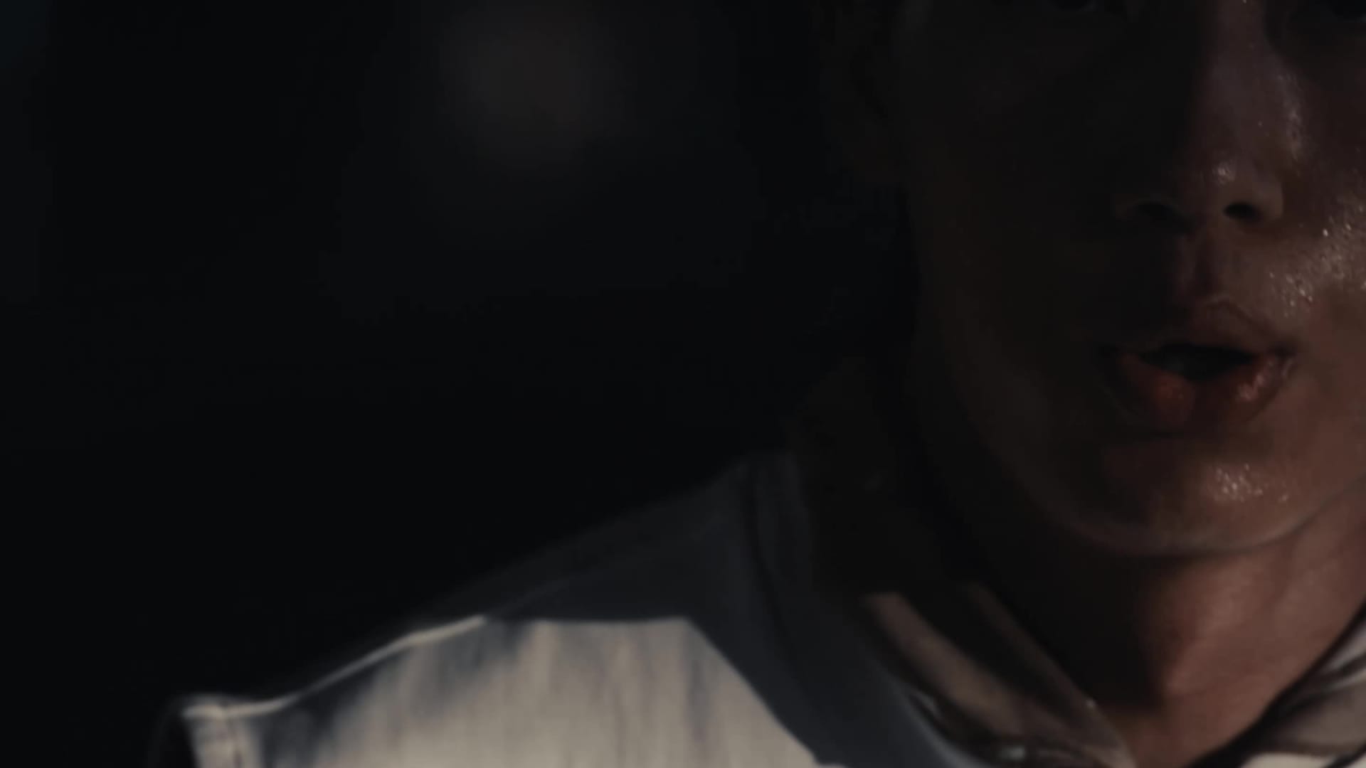 A close-up view of a person's hand wearing a red and white athletic shoe, against a cloudy sky background.