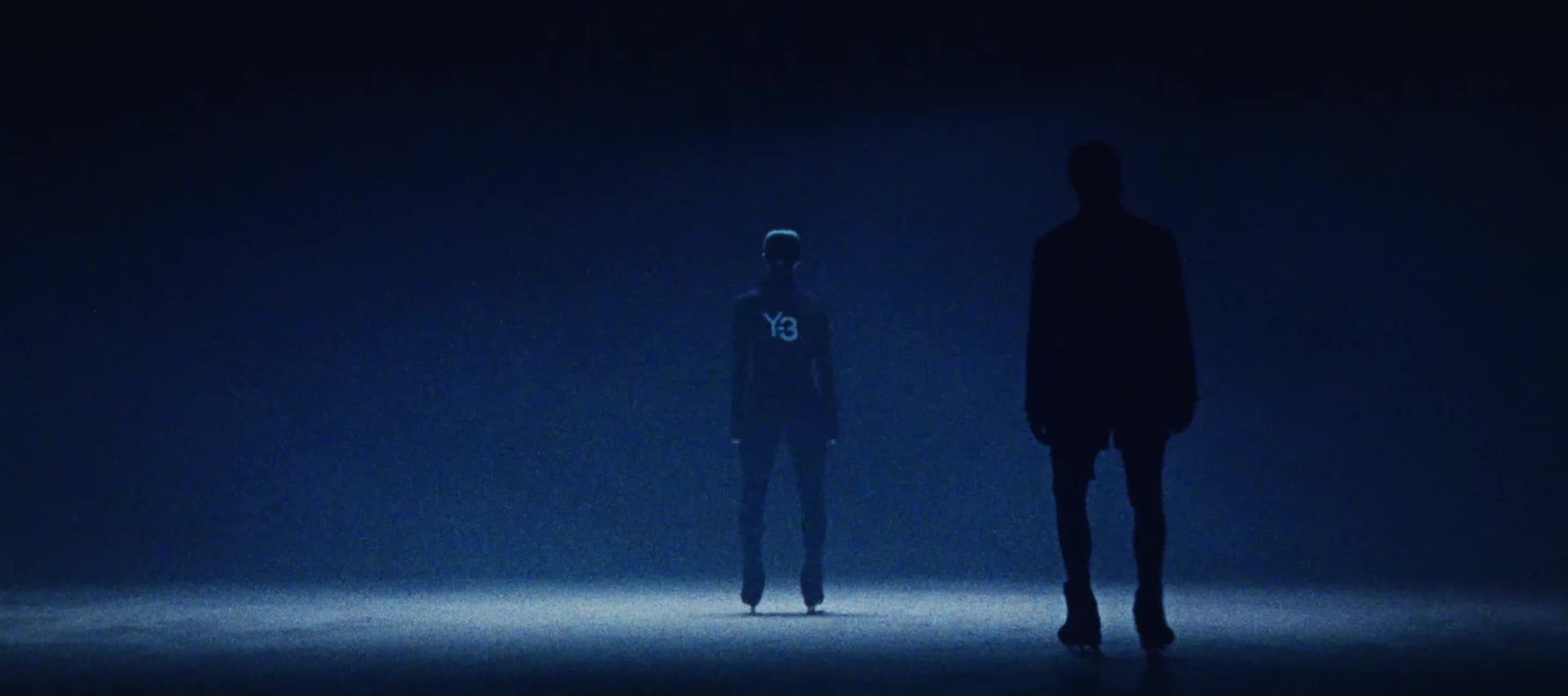 Models dressed in head-to-toe adidas Y-3 apparel skate around a dimly lit ice rink.