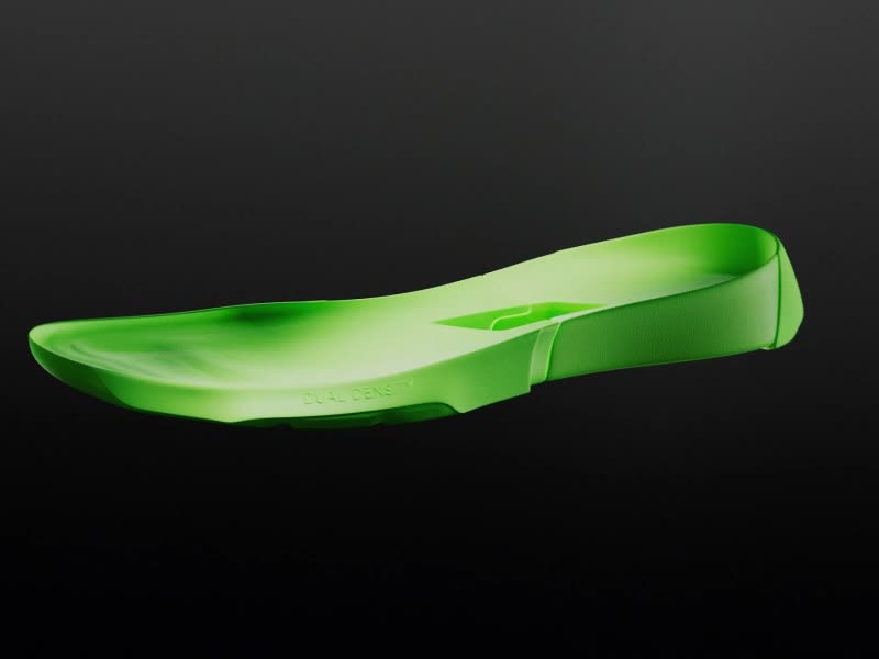 A vibrant green athletic shoe with a distinctive design stands out against a dark background.