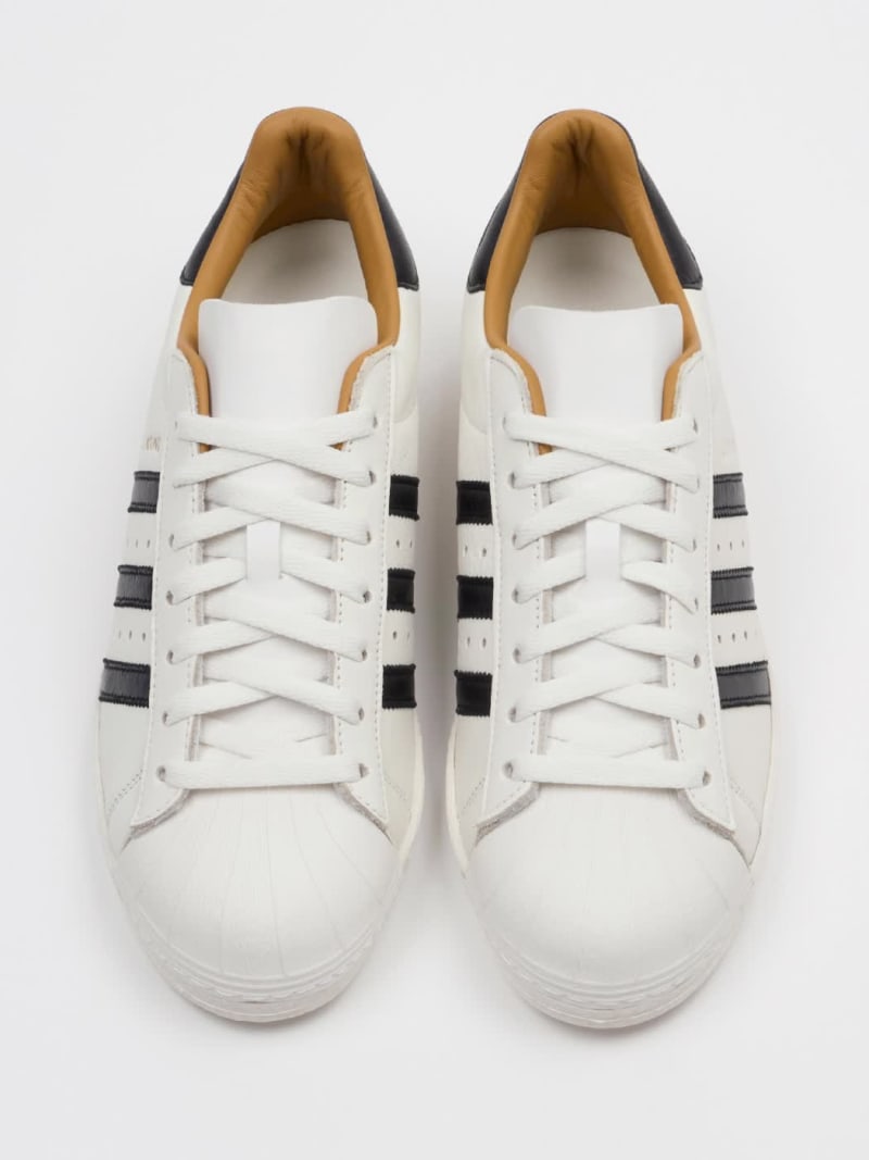 A slideshow showcasing both the white and black versions of the adidas Originals x JJJJound Superstar sneakers.