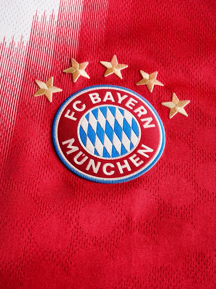 The image shows a man wearing a red and white soccer jersey with the Bayern Munich logo, standing in front of a red background.